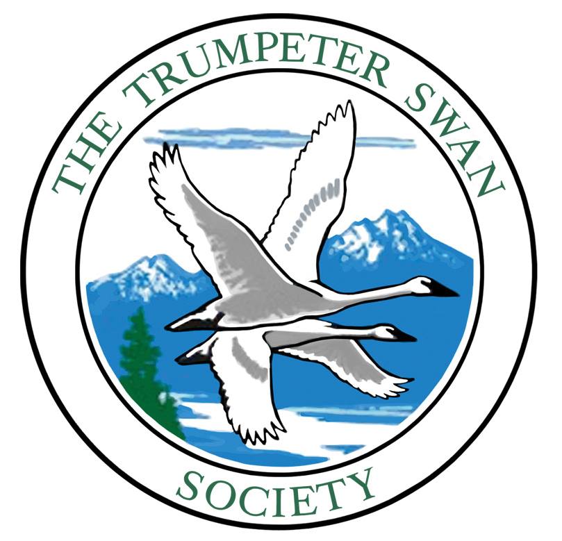 The Trumpeter Swan Society Logo. Circle around two swans flying in front of blue mountains.